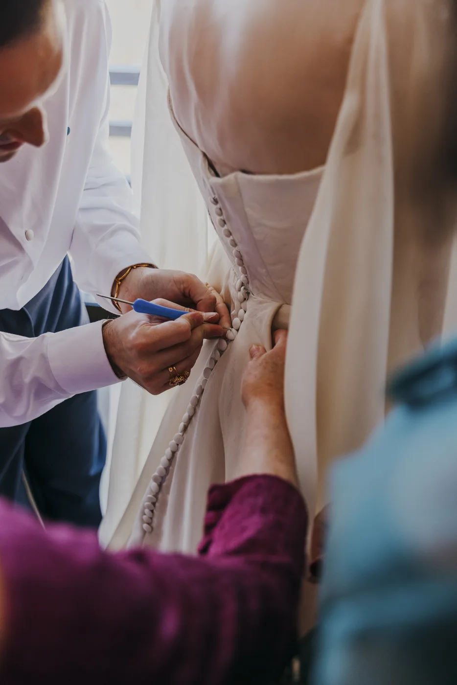 Manos abrochando la botonadura del vestido